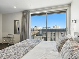 A bedroom with a bed and a mirror at Downtown Haven - Christchurch Holiday Apartment in Christchurch