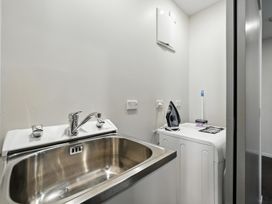 A laundry room with a sink and washing machine at Downtown Haven - Christchurch Holiday Apartment in Christchurch