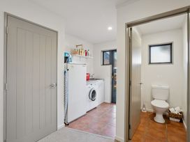 A laundry room with a washing machine and refrigerator at Vista Vale - Wanaka Holiday Home