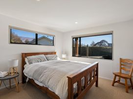 A bedroom with a bed and windows at Vista Vale - Wanaka Holiday Home
