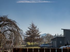 An outdoor view featuring a tree, building, vehicle, and mountains at Vista Vale - Wanaka Holiday Home