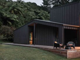 A modern building with a deck and chairs at Lake Rotoiti in Rotorua