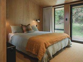 A bedroom with a bed and windows at Lake Rotoiti in Rotorua