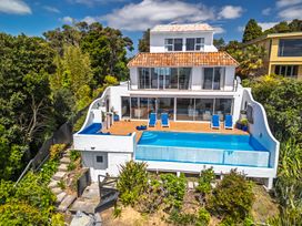 A house with a swimming pool and deck chairs at Seabreeze Sanctuary - Paihia Holiday Home Paihia