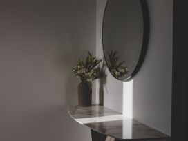 A table with a vase of flowers and a mirror in a hallway at 