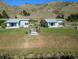 Two houses surrounded by grass and mountains at Tussock Cottage - Canterbury Holiday Home Canterbury
