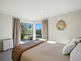A bedroom with a bed and windows at Tussock Cottage - Canterbury