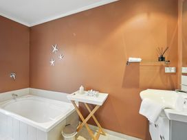 A bathroom with a bathtub and sink at Tussock Cottage - Canterbury Holiday Home in Canterbury