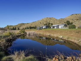 A view of houses near a pond with mountains in the background at Tussock Cottage - Canterbury