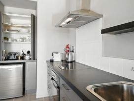 A kitchen with appliances including a refrigerator, stove, and kettle at Flax Cottage - Canterbury Holiday Home, Canterbury