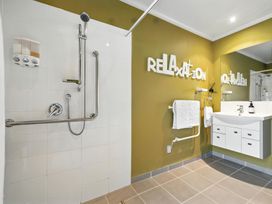A bathroom with a shower, sink, and mirror at Flax Cottage - Canterbury Holiday Home