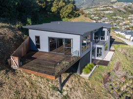 A house with a deck and glass railing on a hillside at Nelson Holiday home in Nelson