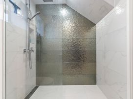 A shower area with glass panel and modern fittings at Sea Breeze - Orewa Oceanside Apartments in Orewa