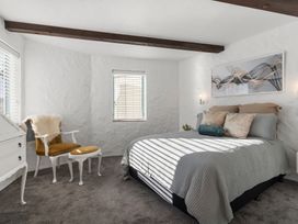 A bedroom with a bed and a chair at Sea Breeze - Orewa Oceanside Apartments in Orewa