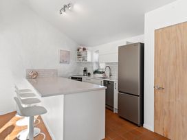 A kitchen with appliances and seating at Sea Breeze - Orewa Oceanside Apartments in Orewa