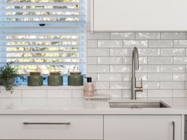 A kitchen with a sink and jars on the windowsill at Sea Breeze - Orewa Oceanside Apartments, Orewa