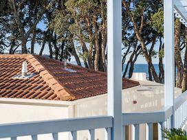 A view of roofs and trees near the ocean at Sea Breeze - Orewa Oceanside Apartments in Orewa