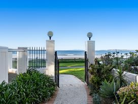 A pathway leading through a gate to the ocean at Sea Breeze - Orewa Oceanside Apartments Orewa