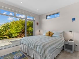 A bedroom with a bed and windows at Mangawhai Heads
