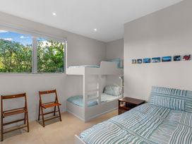 A bedroom with a bunk bed and single bed at Mangawhai Heads
