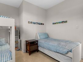 A bedroom with a single bed and bunk bed at Mangawhai Heads