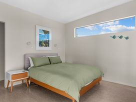 A bedroom with a bed and nightstand at Mangawhai Heads