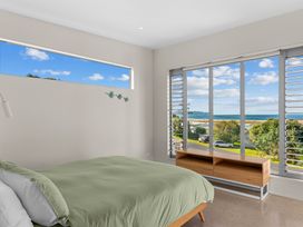 A bedroom with a bed and window view at Mangawhai Heads