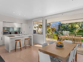 A kitchen with a dining area and outdoor patio at Mangawhai Heads