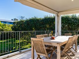 An outdoor patio with a wooden table and chairs at Mangawhai Heads