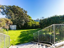An outdoor area with stairs leading down to a lawn and trees at Mangawhai Heads