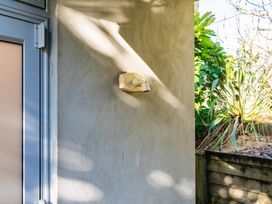 A door and light fixture on a wall with plants beside it at Mangawhai Heads