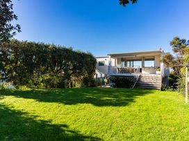 A house with a deck and table in the garden at Mangawhai Heads