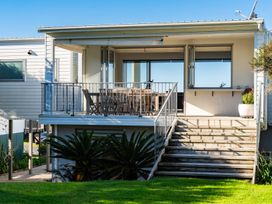 An outdoor deck with a table and chairs at Mangawhai Heads