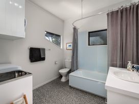 A bathroom with a bathtub, toilet, and sink at Paua Shell - Coopers Beach Holiday Home, Coopers Beach