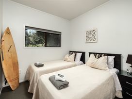 A bedroom with two beds and a surfboard at Paua Shell - Coopers Beach Holiday Home in Coopers Beach
