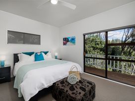 A bedroom with a bed and balcony access at Paua Shell - Coopers Beach Holiday Home
