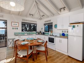 A kitchen with dining table and chairs at Paua Shell - Coopers Beach Holiday Home