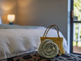 A bedroom with a rolled towel and a basket at Paua Shell - Coopers Beach Holiday Home Coopers Beach