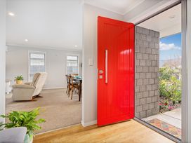 An entryway with a red front door and a dining area visible at Coromandel Holiday Home in Coromandel