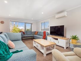 A living room with a television and sofas at Coromandel Holiday Home in Coromandel