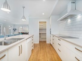 A kitchen with a sink, countertop, and shelves at Coromandel Holiday Home in Coromandel