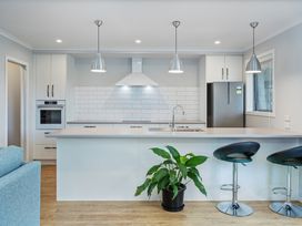 A kitchen with a sink and bar stools at Coromandel Holiday Home in Coromandel