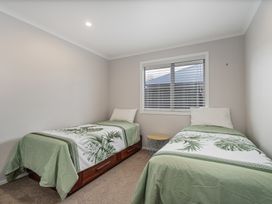 A bedroom with two beds and a side table at Coromandel Holiday Home in Coromandel