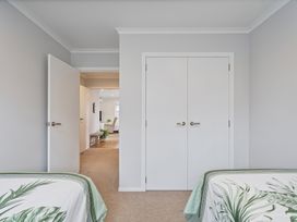 A bedroom with two beds in front of doors at Coromandel Holiday Home, Coromandel