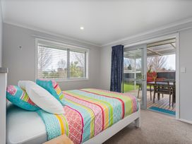 A bedroom with a bed and sliding door to a patio at Coromandel Holiday Home, Coromandel