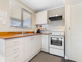 A kitchen with a sink, stove, coffee maker, and orange mugs at All Year Round Adventure Base - National Park