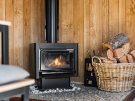 A living room with a wood stove and firewood at All Year Round Adventure Base - National Park