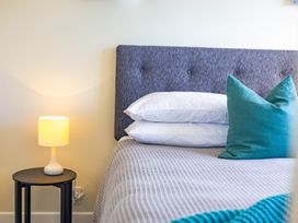 A bedroom with a bed, headboard, pillows, lamp, and side table at All Year Round Adventure Base - National Park