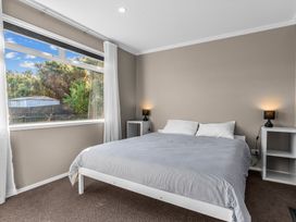 A bedroom with a bed and nightstands at Mangawhai Heads Holiday Home in Mangawhai