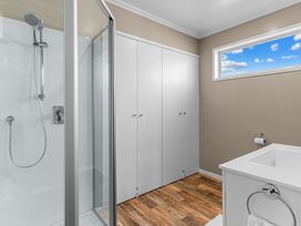 A bathroom with a shower, bathtub, and storage cabinets at Mangawhai Heads Holiday Home in Mangawhai